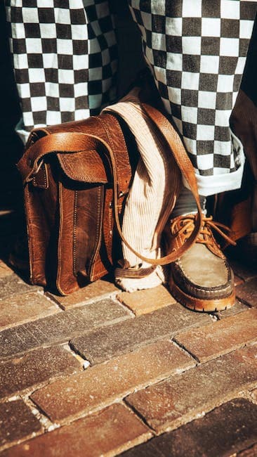 Close-up of leather bag, checkered pants, and vintage shoes on a brick street in Utrecht, Netherlands.