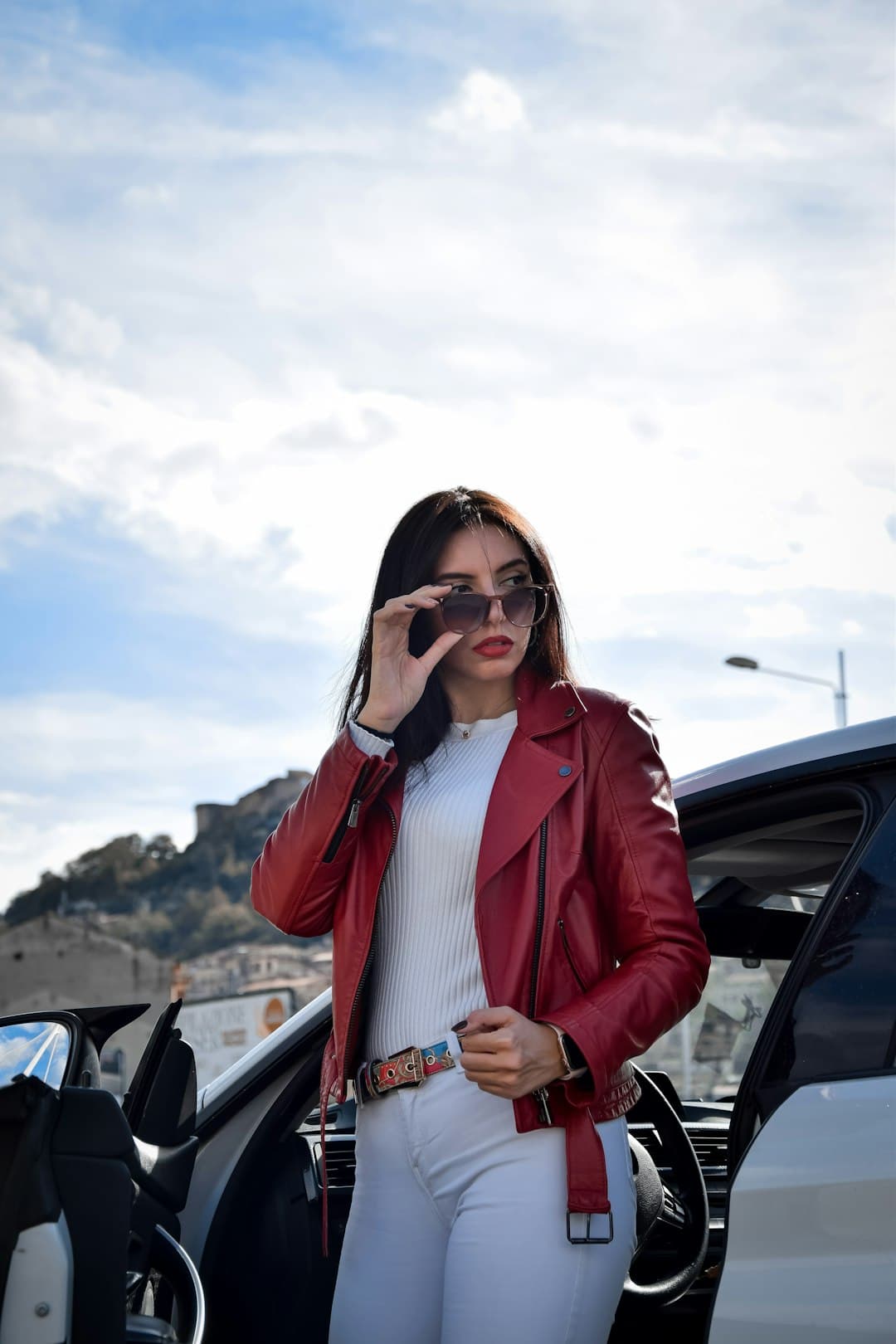 A woman standing next to a car talking on a cell phone